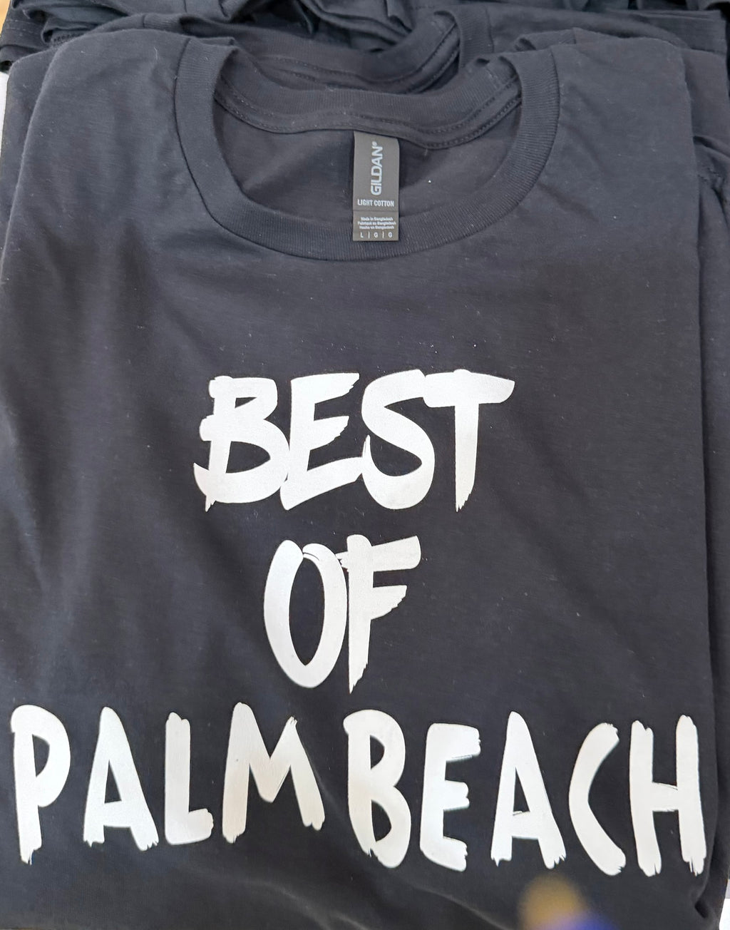 Black t-shirt with 'Best of Palm Beach' text on a folded stack